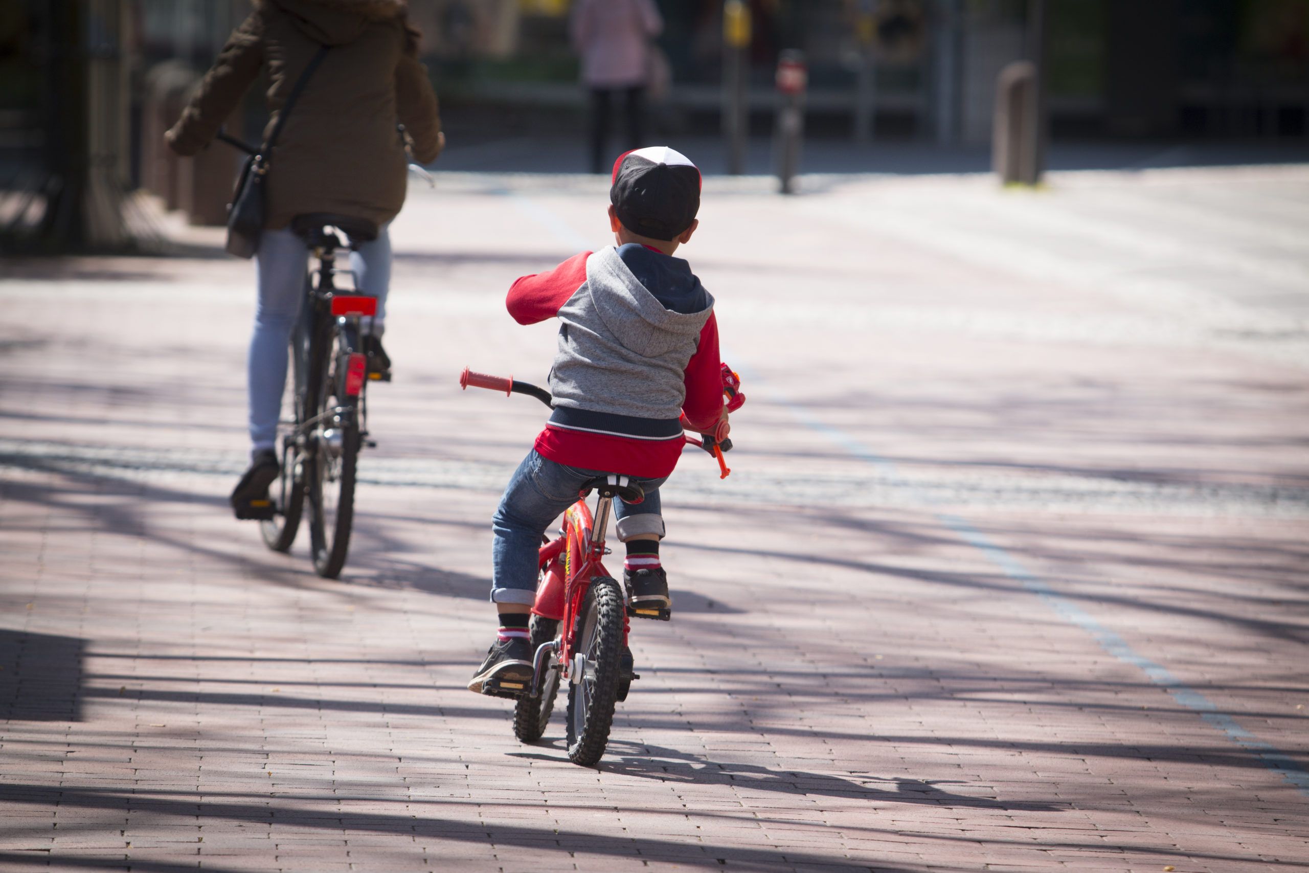 liten pojke som cyklar iväg tillsammans med en förälder