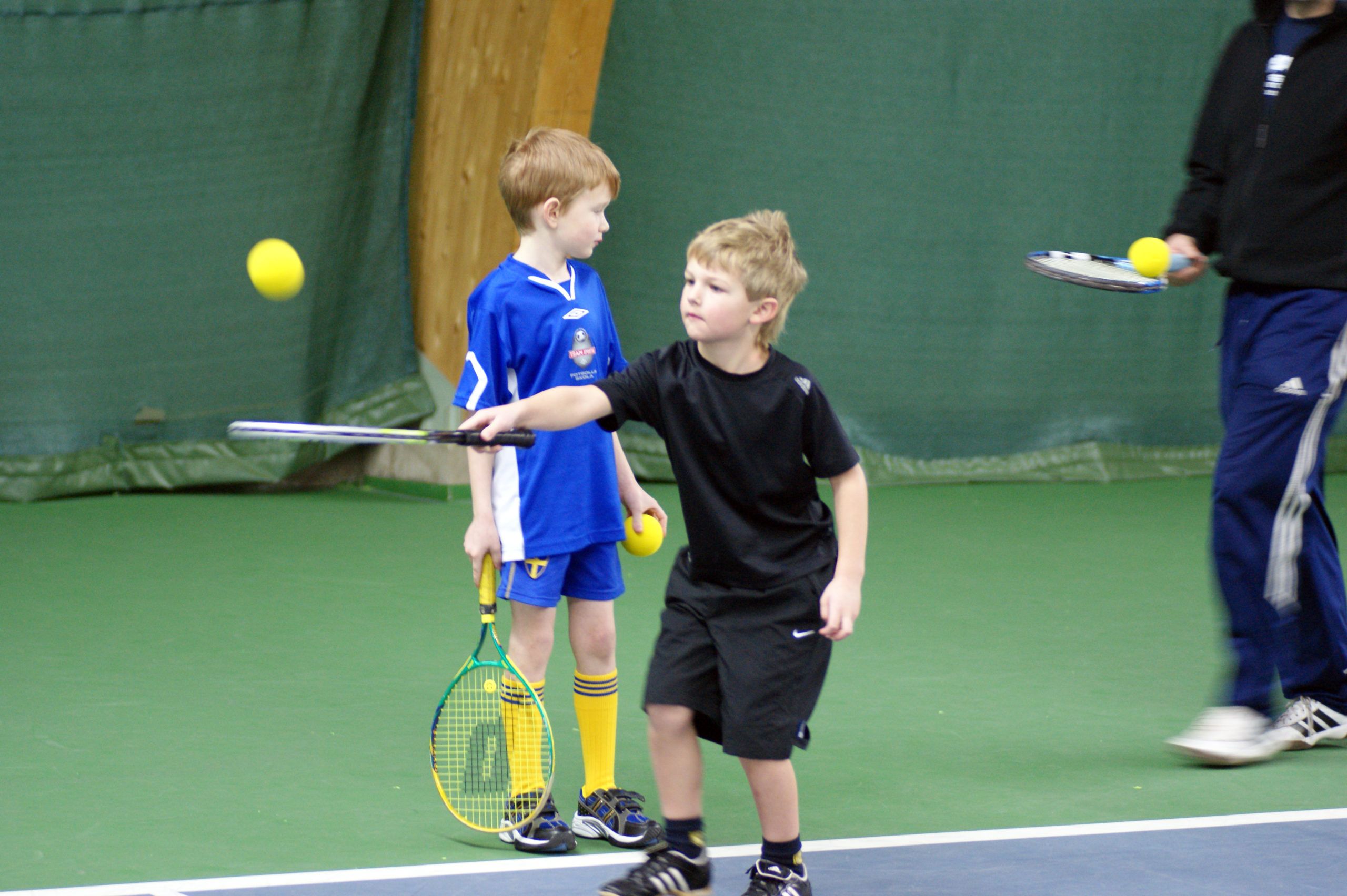 pojkar som provar på att spela tennis
