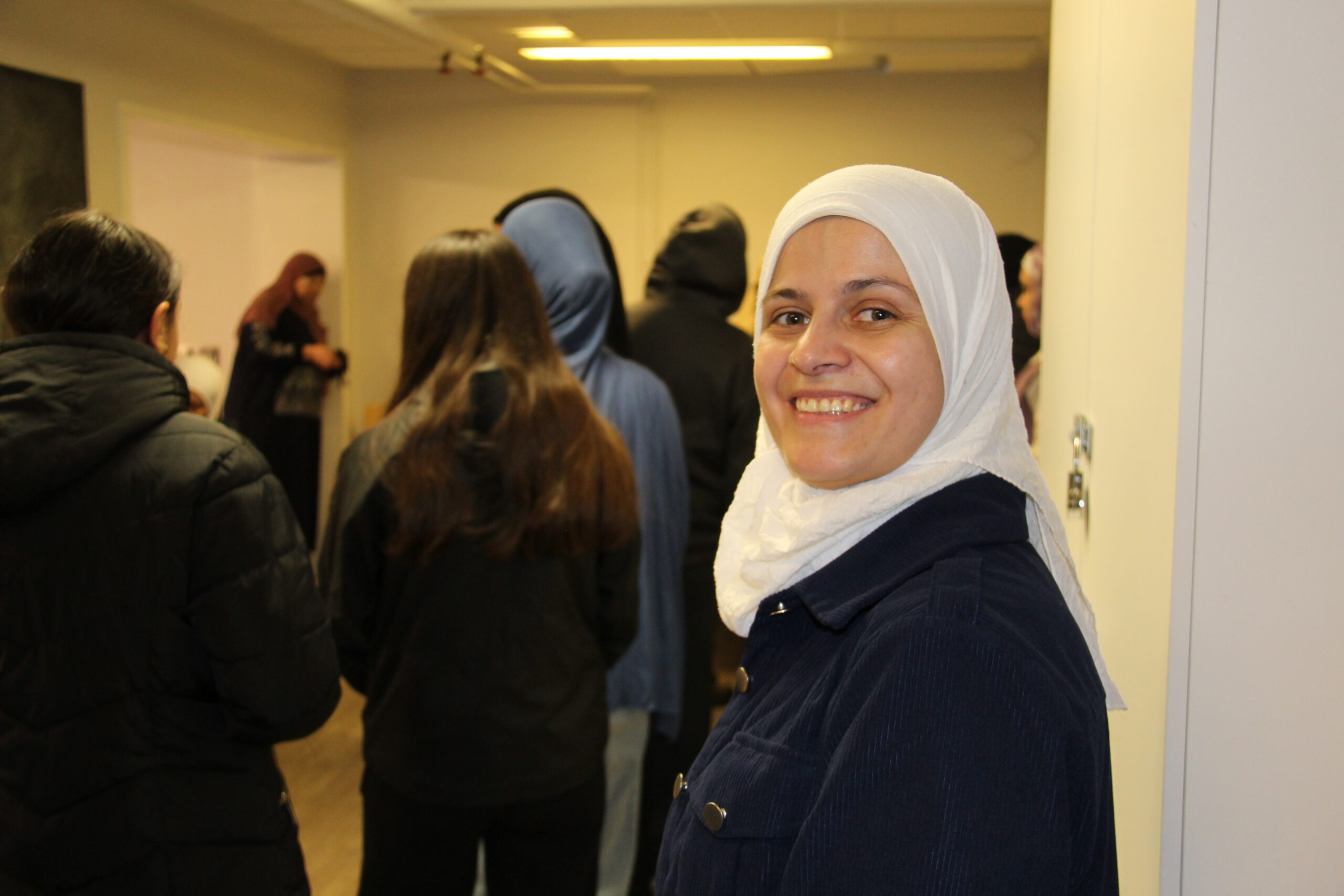 glad kvinna i slöja framför en kö av människor