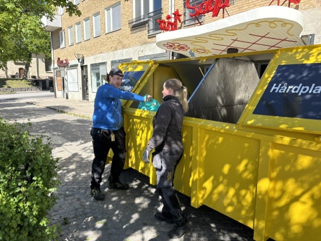 Två personer som slänger skräp i en gul container